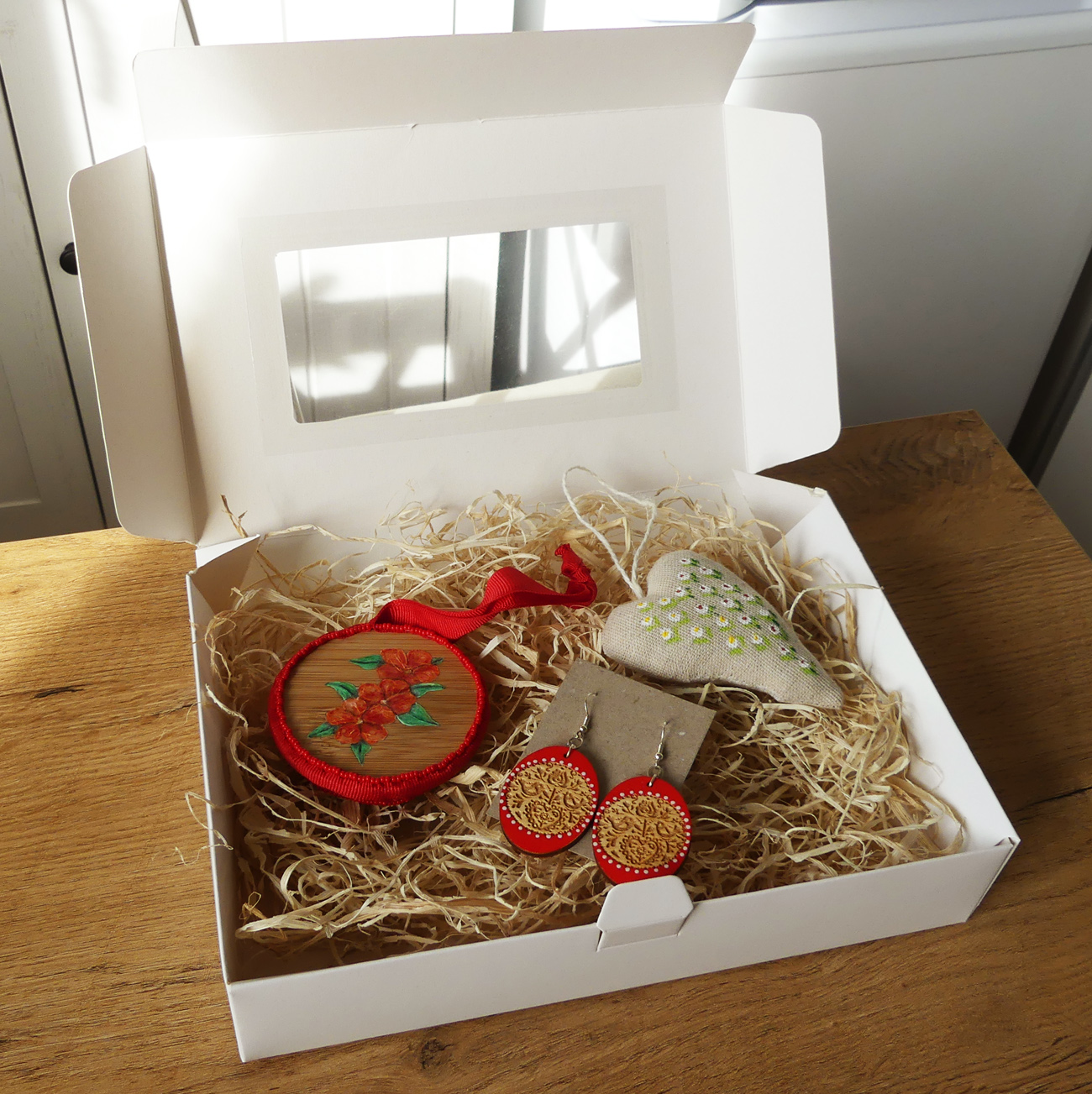 Červený darčekový box s folklórnymi náušnicami a dekoráciami
