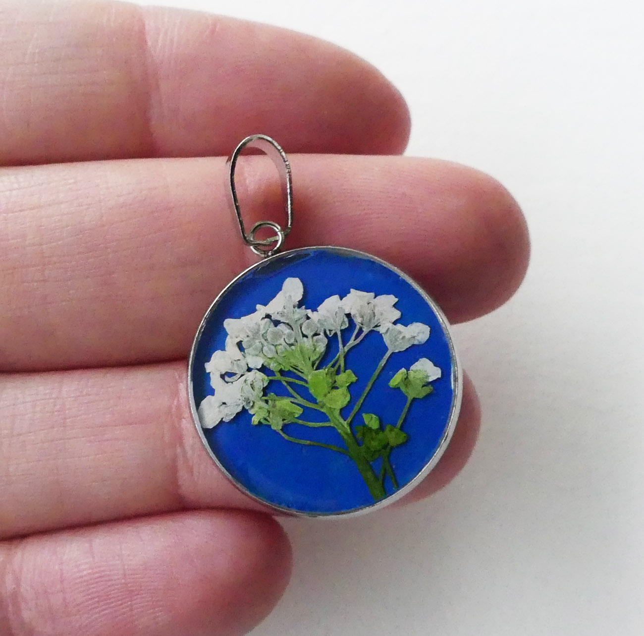 Biely kvet na modrom podklade - handmade živicový prívesok z chirurgickej ocele