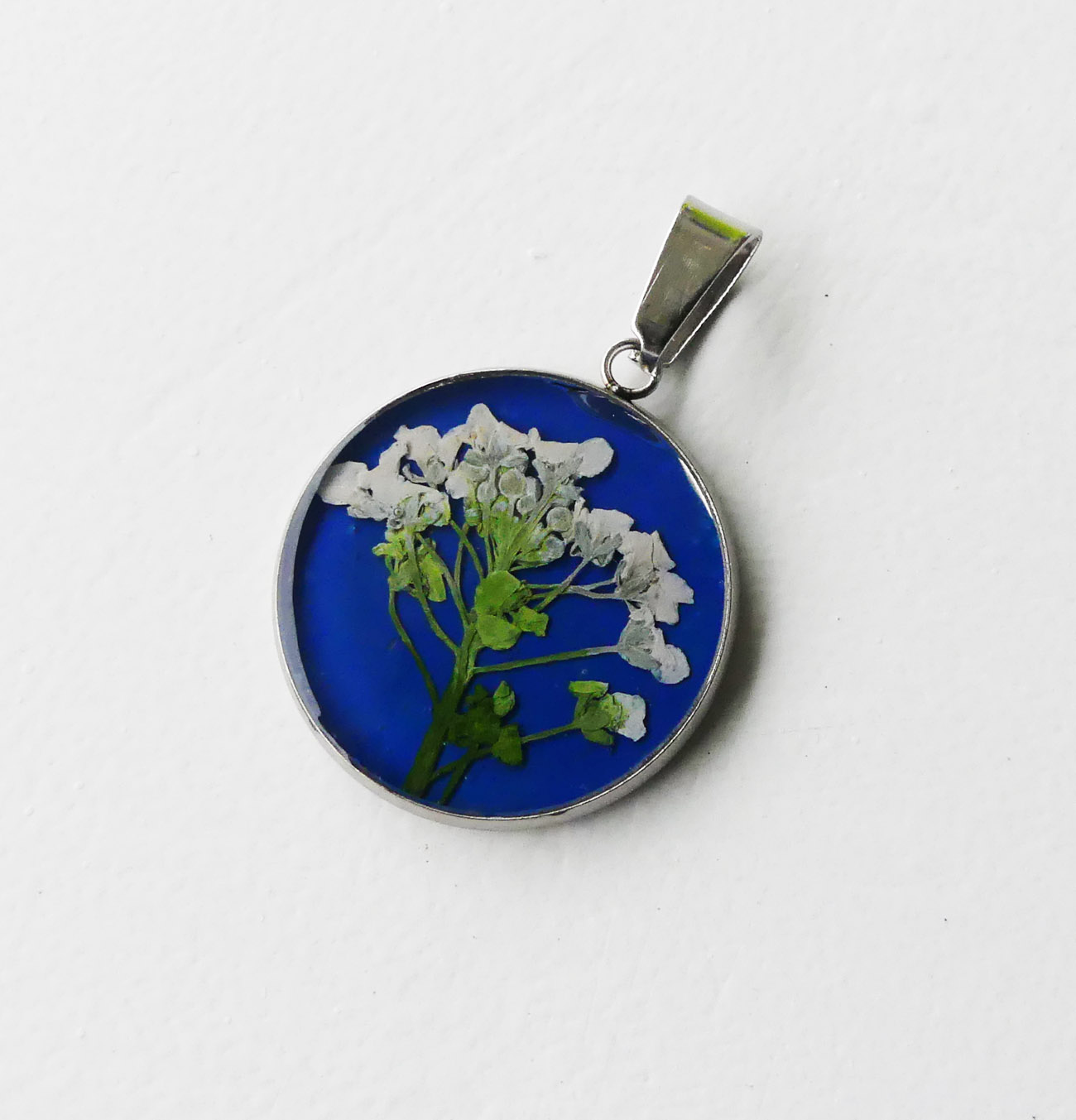Biely kvet na modrom podklade - handmade živicový prívesok z chirurgickej ocele